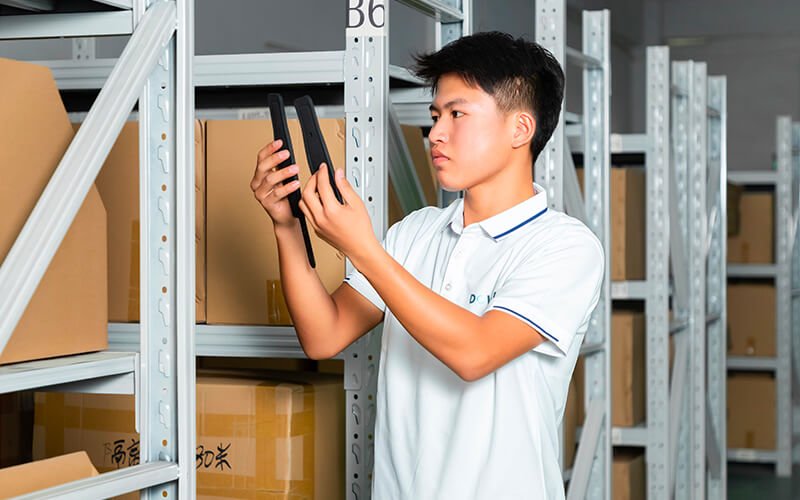 a male worker in Dowch uniform is checking goods in a warehouse